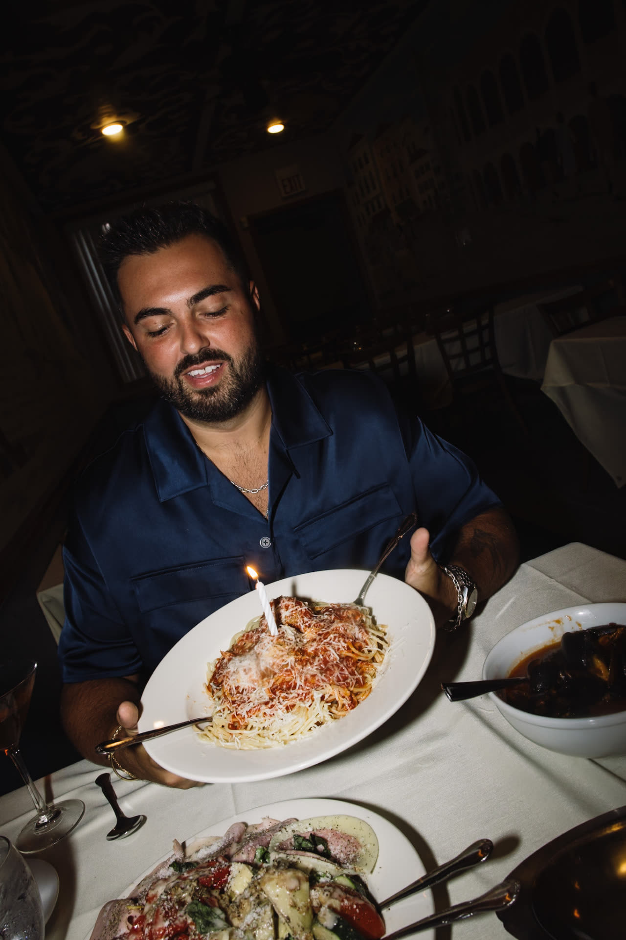 Dom C twirling a plate of pasta in a dim dining room